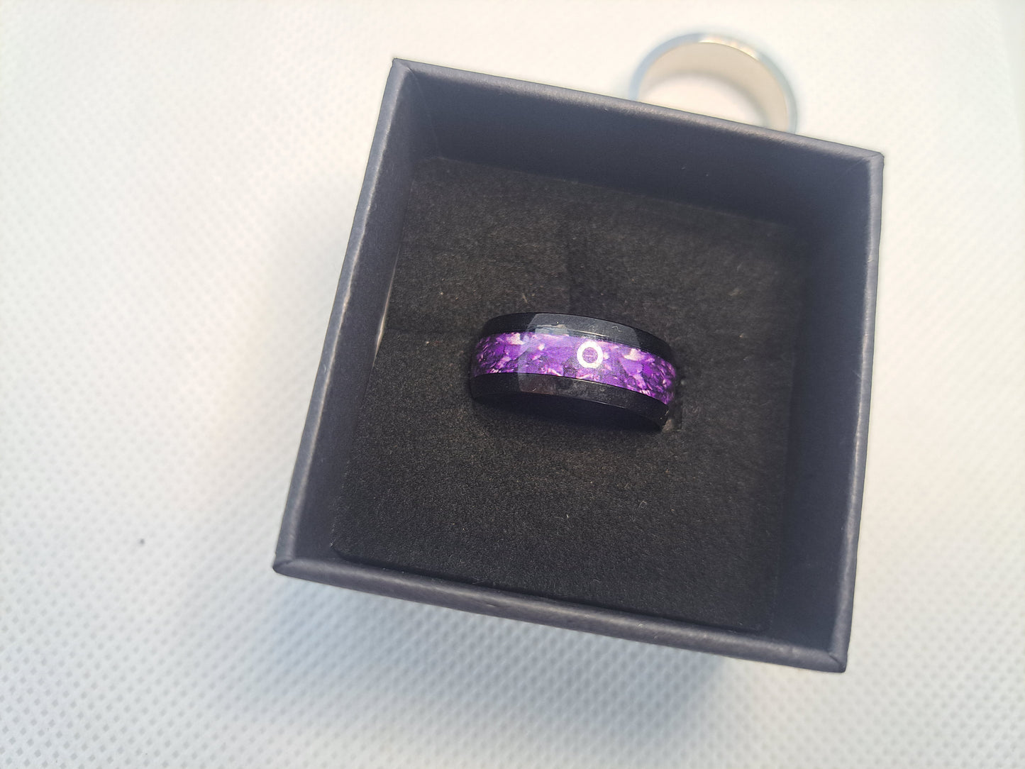 Black ring with purple swirl inlay design in a black box.