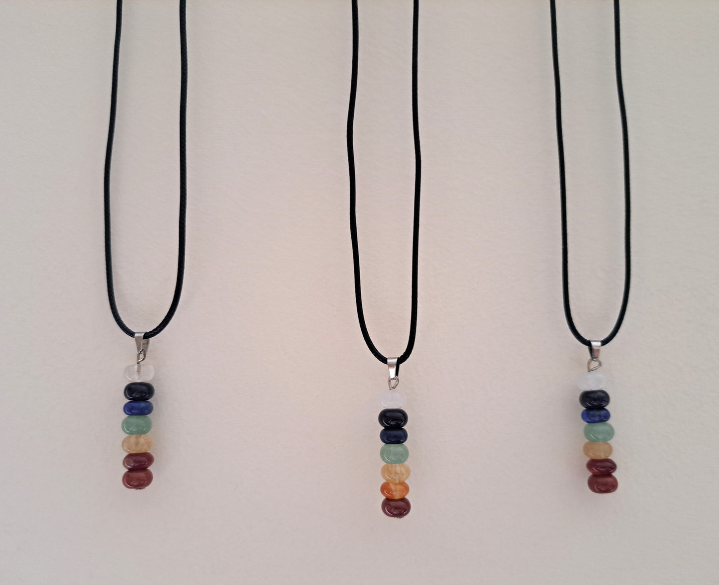 Three chakra beaded necklaces hanging against a white background.